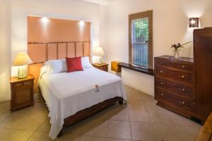 a bedroom with a large bed and a dresser at Hotel Villas El Encanto Cozumel in Cozumel