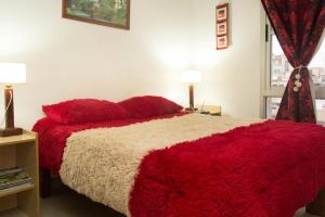 1 dormitorio con 1 cama roja y blanca y 2 lámparas en Salta,Departamento Para Visitar la Virgen Del Cerro o Viaje De Placer en Salta