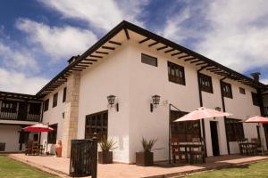 a white building with umbrellas in front of it at Casona Quesada in Suesca