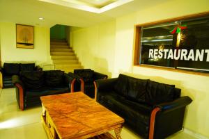 a waiting room with black leather couches and a table at Green Park Residency in Kannur