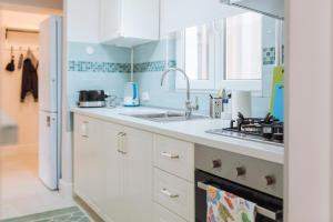 una cocina con armarios blancos y fregadero en River View - Old City Apartment en Bucarest