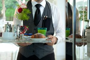 a man in a suit holding a tray of food at Hotel La Floridiana in Capri