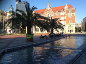 a pool of water with palm trees in front of a building at Apartament Sorello - Katowice Centrum in Katowice