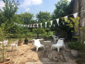 un patio con sillas blancas, mesas y banderas en Villa Pacchioni, en Cavezzo