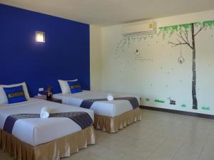 甲米镇Forum House Hotel Krabi的墙上挂着一幅树壁画的房间里,有两张床