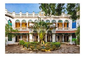 ein großes Gebäude mit einer Palme davor in der Unterkunft Chettinadu Mansion – An Authentic Heritage Palace in Kānādukāttān