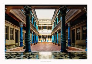 a hallway of an old building with blue columns at Chettinadu Mansion – An Authentic Heritage Palace in Kānādukāttān