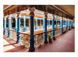 eine Reihe blauer Säulen auf einem Balkon eines Gebäudes in der Unterkunft Chettinadu Mansion – An Authentic Heritage Palace in Kānādukāttān