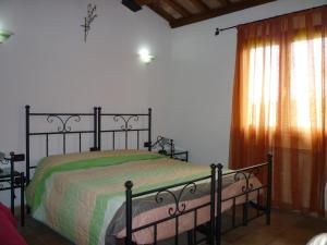 a bedroom with a bed with a green blanket and a window at Tadinum Romana in Gualdo Tadino