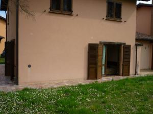 a house with brown shutters and a green yard at Tadinum Romana in Gualdo Tadino