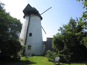 a windmill with a bench in front of it at home in the Flemish Ardennes between the meadows in Sint-Kornelis-Horebeke