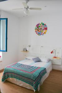 Dormitorio blanco con cama y reloj en la pared en El Taller del Abuelo, en Córdoba