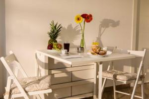 a white table with a bowl of fruit and a vase of flowers at fiori e massi in Ostuni