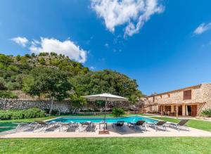 a villa with a swimming pool with chairs and an umbrella at Pontarro in Pollença