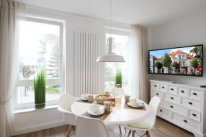 a white dining room with a white table and chairs at Min Hüsung by Rujana in Binz