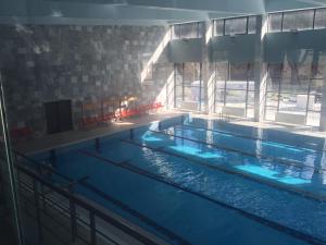a large swimming pool with blue water in a building at Guest Apartment Monarch in Smolyan
