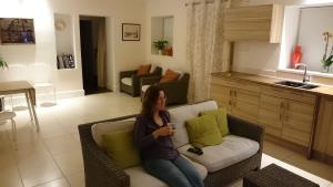 kobieta siedząca na kanapie w salonie w obiekcie The Lawns Spa Apartment w mieście Holt