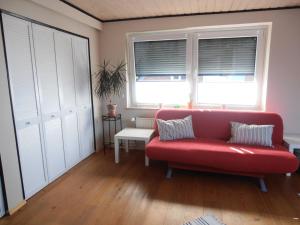 a living room with a red couch and two windows at Privatzimmer Frank in Tarp