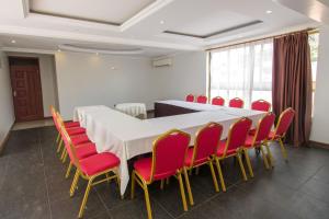 a conference room with a long table and red chairs at Victoria Comfort Inn in Kisumu