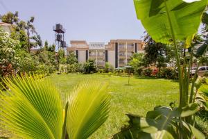 un parc verdoyant avec un grand bâtiment en arrière-plan dans l'établissement Victoria Comfort Inn, à Kisumu