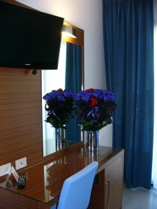 een bureau met twee vazen met paarse bloemen erop bij Hotel Serena in Grado