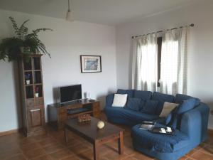 sala de estar con sofá azul y mesa en Casa Chona, en Tinajo