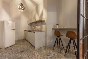 La cuisine est équipée d'un réfrigérateur et de deux tabourets de bar. dans l'établissement Suite Cagliari -101-, à Cagliari