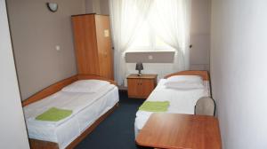 two beds in a small room with a table and a tableablishthritisthritisthritis at Zajazd Fadom in Łomża +21 photos