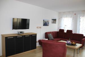 a living room with a red couch and a tv at Villa Gutenberg in Binz