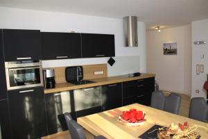a kitchen with black cabinets and a wooden table at Villa Gutenberg in Binz +5 photos