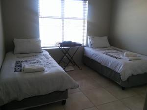 two beds in a small room with a window at Marina Martinique Selfcatering in Jeffreys Bay
