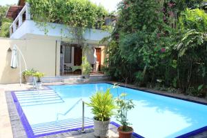 a swimming pool in front of a house with plants at Villa Tara in Hikkaduwa