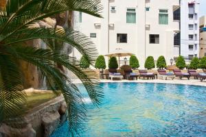 a palm tree in front of a building with a swimming pool at LK Metropole (Junior Wing) in Pattaya Central