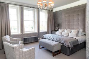 a bedroom with a bed and a chair and windows at The Dowans Hotel of Speyside in Aberlour