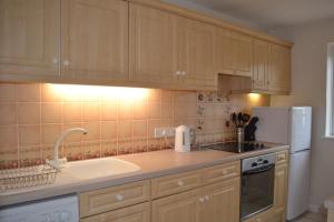 a kitchen with wooden cabinets and a sink and a refrigerator at 2 Bedroom Apartment in Stratton Court Central Surbiton incl Free Parking in Kingston upon Thames