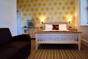 a bedroom with a bed and a couch and a television at Healds Hall Hotel in Cleckheaton