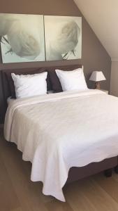 1 cama grande con sábanas y almohadas blancas en B&B Soluna, en Oostduinkerke