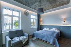 a bedroom with a bed and a chair and windows at 9010 Apartments in Vilnius