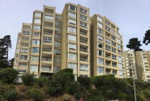 a tall apartment building with trees in front of it at Departamento en la Playa in Algarrobo