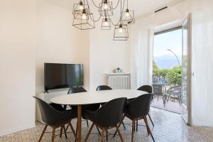 una sala da pranzo con tavolo, sedie e TV di La Promenade by Impero House a Stresa