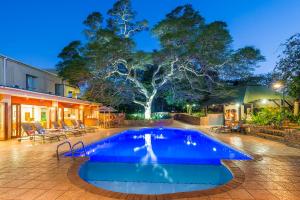 a swimming pool in front of a house with a tree at ANEW Hotel Hluhluwe in Hluhluwe