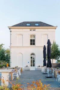 a white building with tables and umbrellas in front of it at Boutique Hotel De Witte Dame in Abcoude