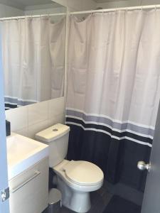a bathroom with a white toilet and a shower curtain at Apto Bahia Horizonte - La Herradura in Coquimbo