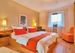 Un dormitorio con una cama con almohadas rojas y una ventana en Haus Carola en Bodenmais