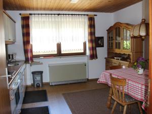 eine Küche mit einem Tisch und 2 Fenstern sowie einem Tisch und Stühlen in der Unterkunft Vronis Ferienwohnungen in Mühlingen