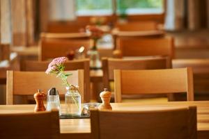 una mesa de madera con un jarrón de flores. en Seminar- und Gästehaus im Kloster Bezau, en Bezau