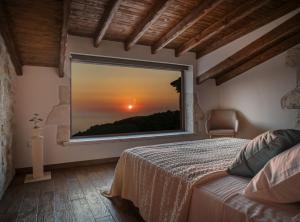 ein Schlafzimmer mit einem Bett und einem Fenster mit Blick auf den Sonnenuntergang in der Unterkunft Villa Amara Private Estate in Anafonítria