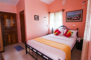 a bedroom with a bed with orange walls and a window at Hilias Retreat in Palolem