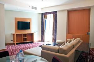 فندق رامي روز في دبي: غرفة معيشة مع أريكة وتلفزيون بشاشة مسطحة