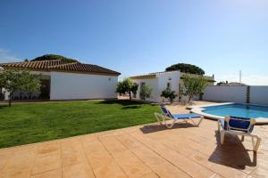 un patio trasero con piscina, 2 sillas y una casa en casa Garcia, en Conil de la Frontera